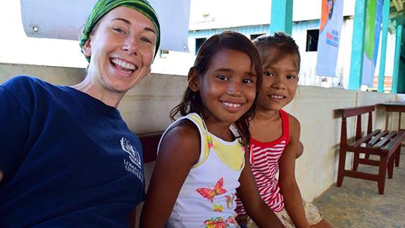 Student smiling with children from Belize